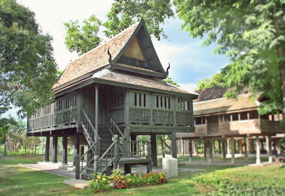 Elevated Lanna teak house with ornate gable and carved balustrade at the museum